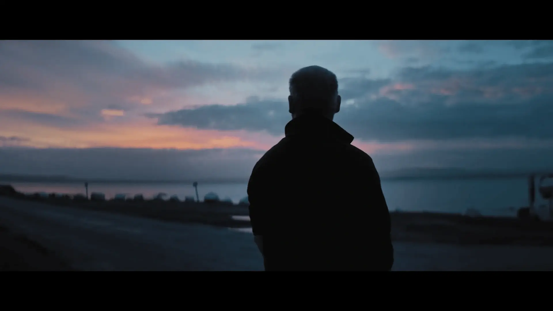 From the short film 'The Botanist' directed by Zach Joseph with cinematography by Paolo Bischi. Image features a man in front of a sunset looking out to the horizon.