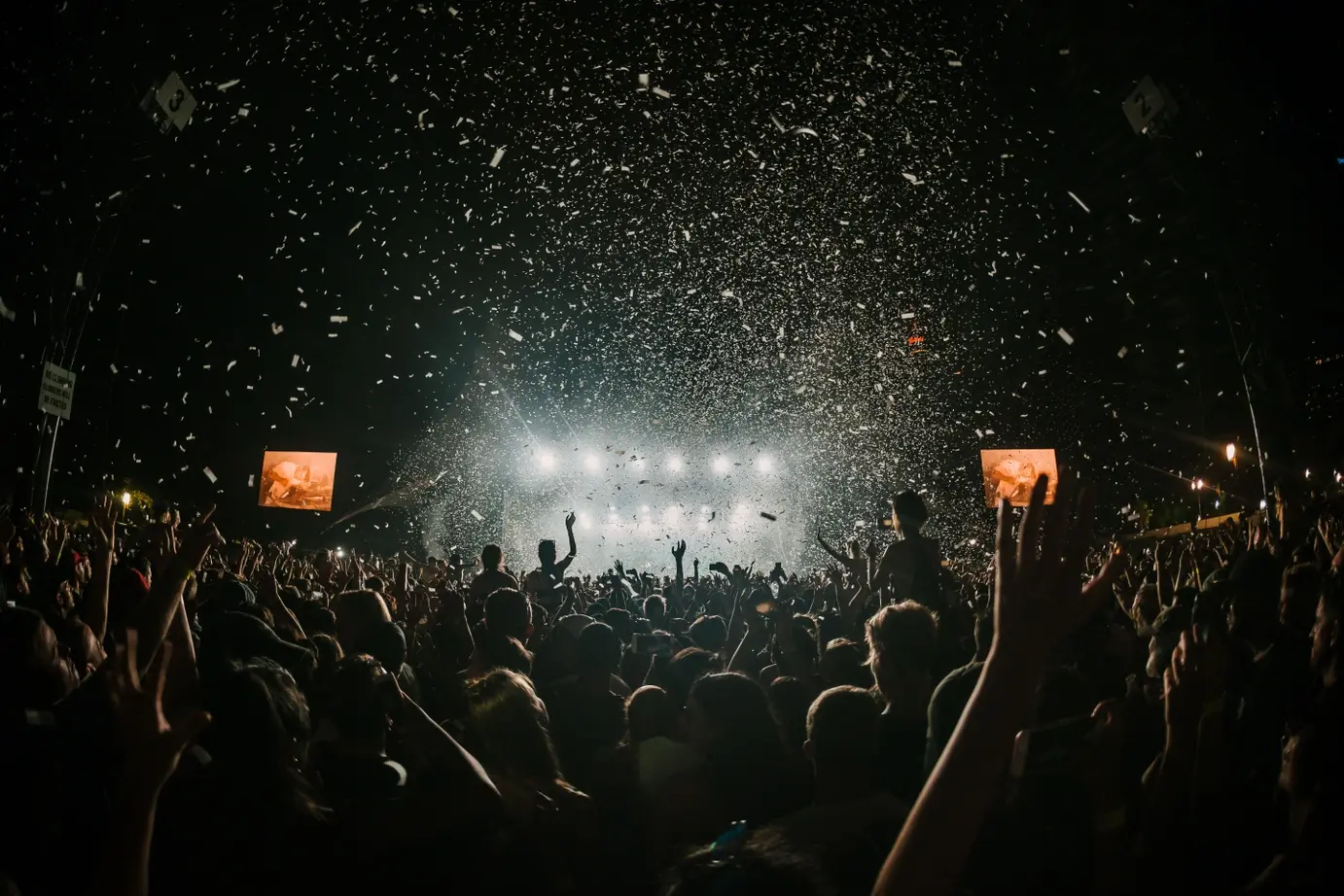 Cinemagraphic photo of a large group of people enjoying a rock concert with concert lights beaming down. Image by Danny Howe on Unsplash.