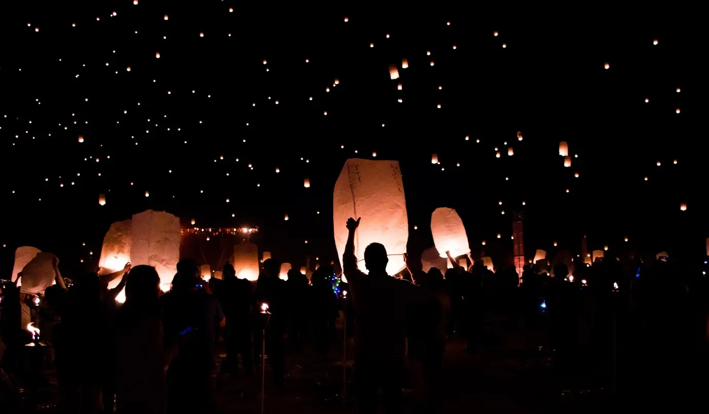 Many people releasing lanterns into the night sky at a lantern festival. Image by Ryan Franco on Unsplash.