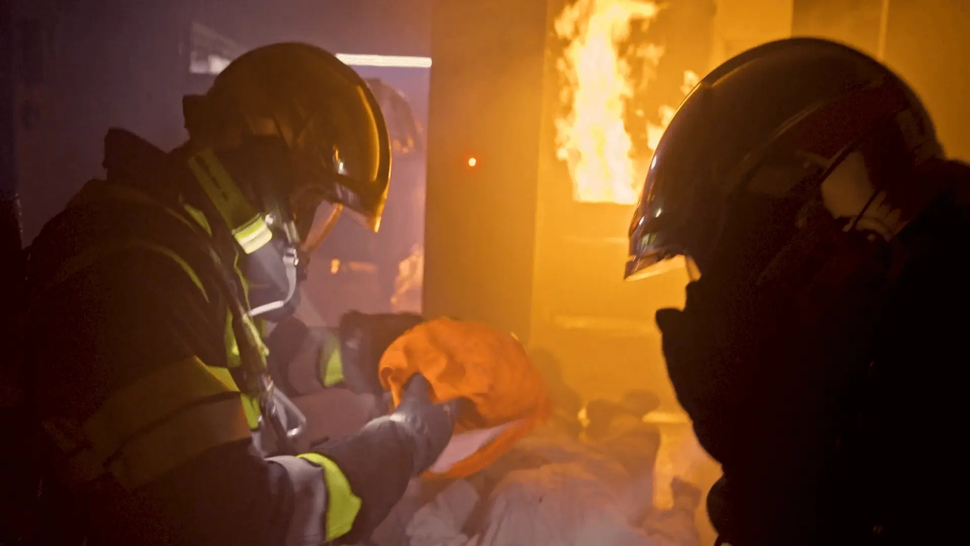 Screenshot from the Ford 'Lifesavers' documentary series, depicting 2 fire fighters entering a burning building.
