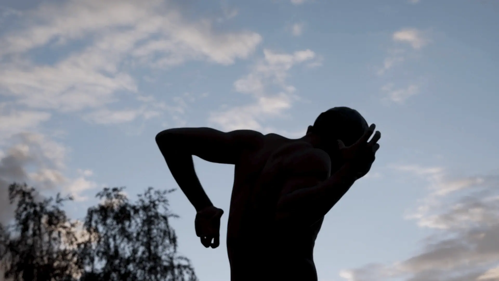 Screenshot from spokenword film 'Bodies' directed by Davy Lazare. Image depicts a man performing an expressive dance to the backdrop of a morning's sky.